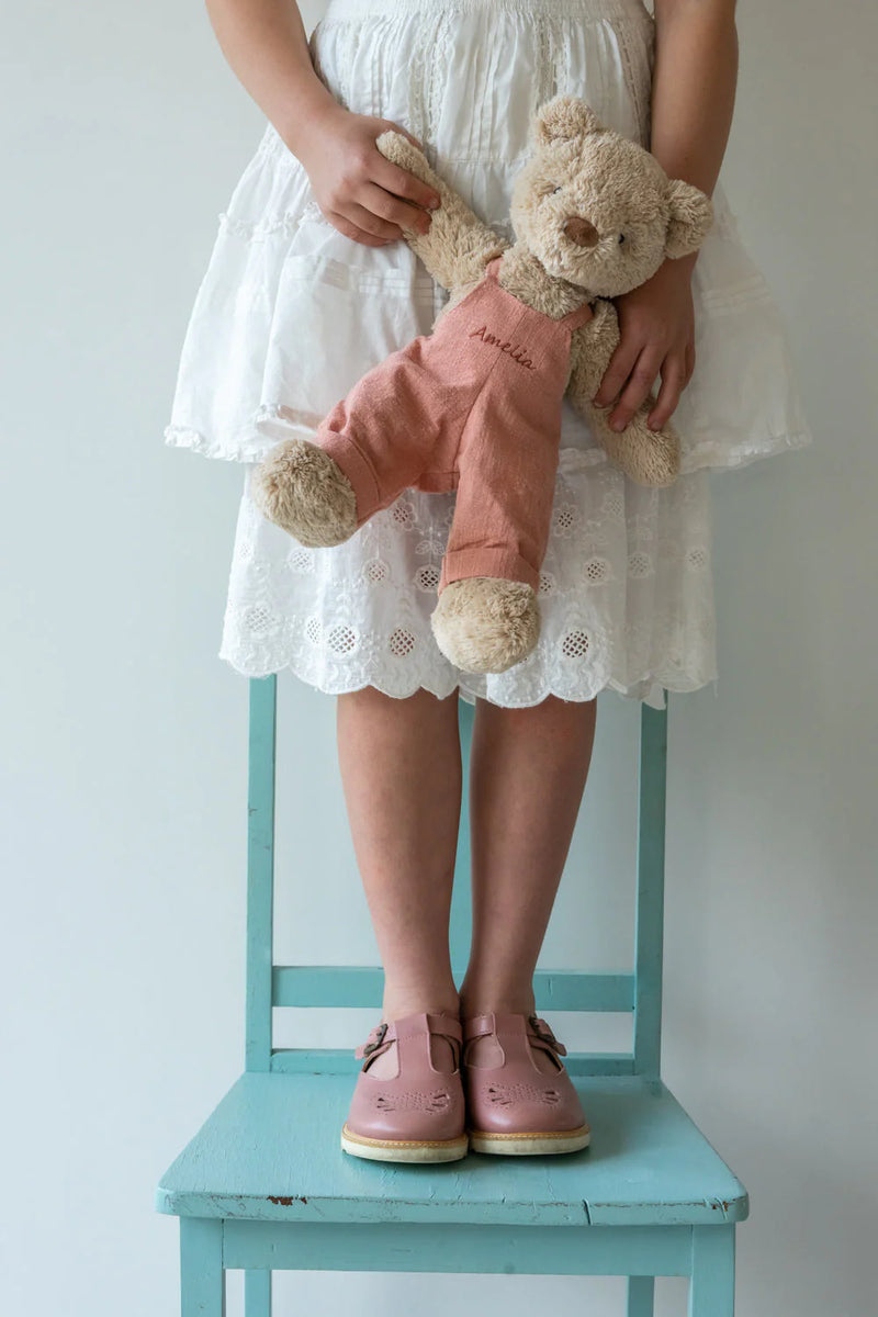 a girl stand on a blue chair holding her nana huchy soft bear toy