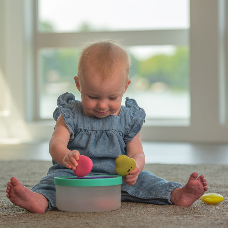 a baby puts toys into the bucket