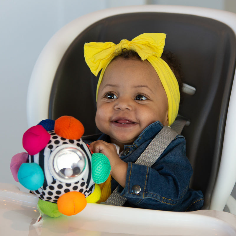 little baby smiles and plays with the fabric baby ball