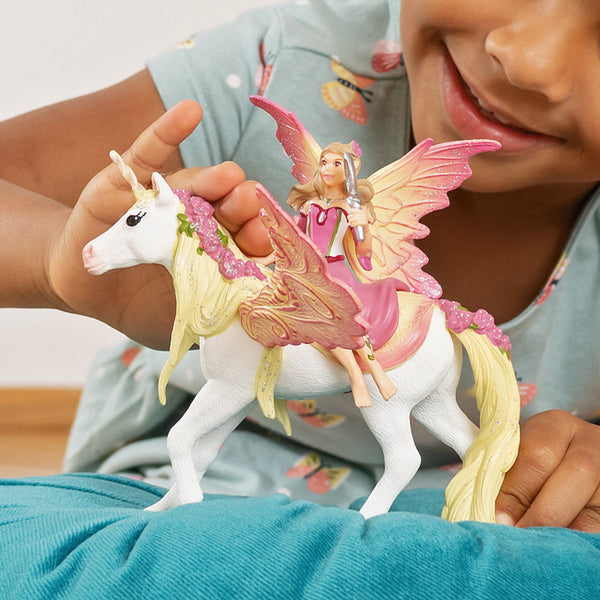 a child holds her schleich fairy feya on a white unicorn 